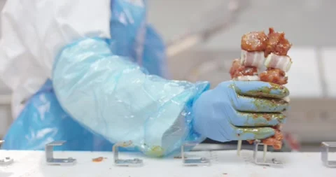 Worker skewering marinated pork kebabs on production table, Slow Motion Stock Footage 340032144