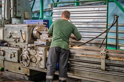 A worker skillfully operates a lathe machine in a factory, shaping metal part Foto stock