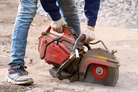 A worker skillfully uses a concrete cutoff saw on a construction site for Stock Photos
