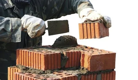 Worker skillfully uses a trowel to lay bricks while assembling a sturdy wall Stock Photos