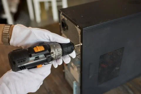 A Worker Skillfully Using a Power Drill for the Purpose of Computer Repair and Stock Photos