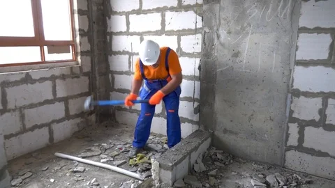 Worker with a sledgehammer breaks a wall, the wall collapses Stock Footage 115438034