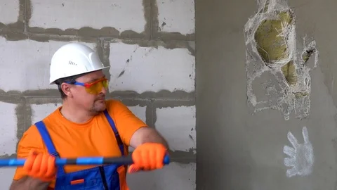 Worker with a sledgehammer breaks a wall, the wall collapses Stock Footage 115438814