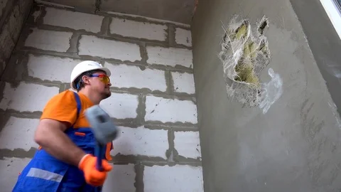 Worker with a sledgehammer breaks a wall, the wall collapses Stock Footage 115438873