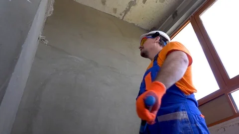 Worker with a sledgehammer breaks a wall, the wall collapses Stock Footage 115439227