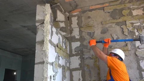 Worker with a sledgehammer breaks a wall, the wall collapses Stock Footage 115439506