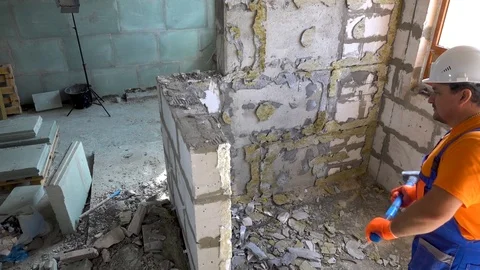 Worker with a sledgehammer breaks a wall, the wall collapses Stock Footage 115439572