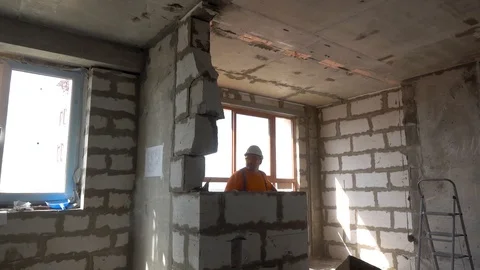 Worker with a sledgehammer breaks a wall, the wall collapses Stock Footage
