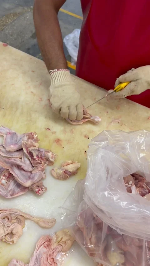 Worker slicing raw chicken meat on table, vertical close-up Stock Footage 345164765