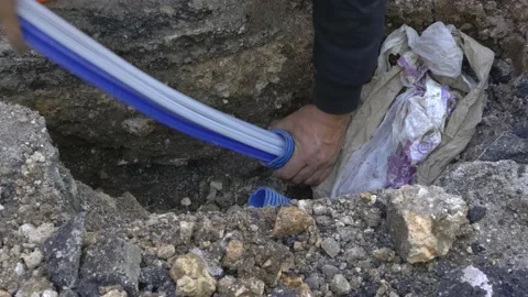 Worker slips fiber optic cables into underground corrugated pipe Video stock 148373498
