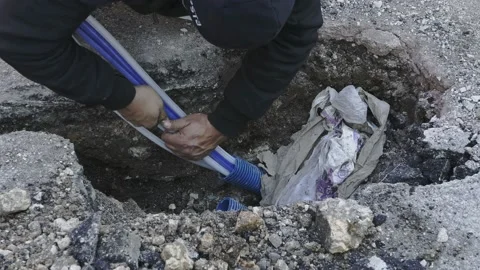 Worker slips fiber optic cables into underground corrugated pipe Stock-Footage 157386180