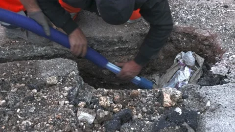 Worker slips fiber optic cables into underground corrugated pipe Video stock 172596180