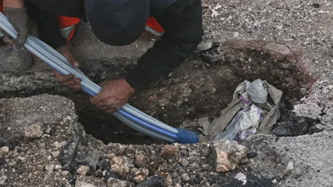 Worker slips fiber optic cables into underground corrugated pipe Video stock 211367106