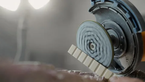 Worker smoothing ceramic tile end with tile cutter on workbench during a home Stock Footage 320263903