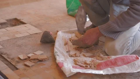 Worker smoothing an object with a hammer on a building site to build house Видео 110771520