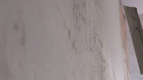 Worker smoothing plaster on wall with hand trowel during renovation Stock Footage 346551213