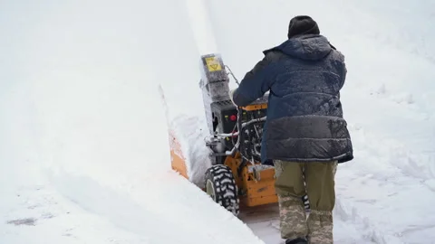 Worker with snow blower removing snow after winter storm, snow thrower assisting Stock Footage 259864306