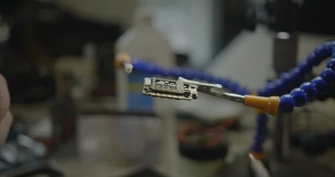 Worker soldering a piece of computer chip in a factory. Stockbeeldmateriaal 122251983
