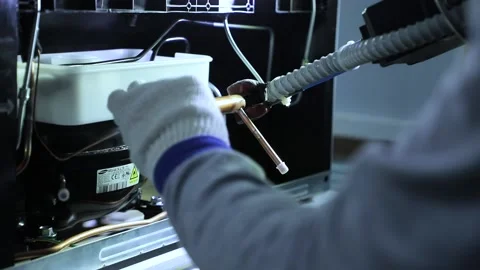 Worker solders copper pipes of compressor in refrigerator Stock Footage 160505472