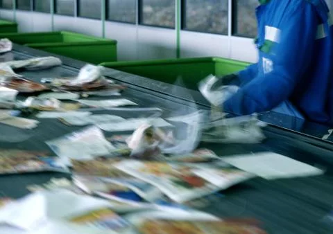 Worker sorting paper on conveyor belt for recycling Stock Photos