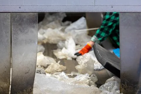 Worker sorting plastic waste on conveyor belt in recycling plant 库存照片