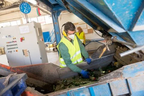 Worker is sorting the recyclable glass material and removing non recyclable t Stock Photos