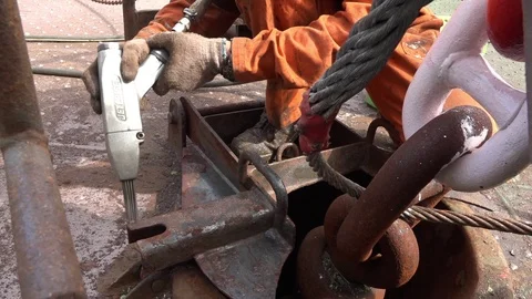 Worker in special jumpsuit removes rust from vessel element Stock Footage 113454752
