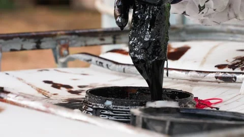 Worker in special protective clothing holds black hose, fills crude oil barrel Stock Footage 286340791
