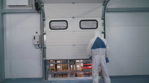 A worker in a special uniform opens a warehouse Stock Footage 145694579