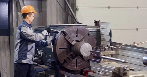A worker spins a metal part for processing at a factory Stock Footage 160657730