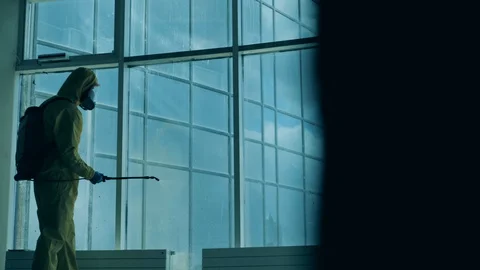 Worker in a splash suit is disinfecting a window. Coronavirus pandemic, virus Stock Footage 129515749