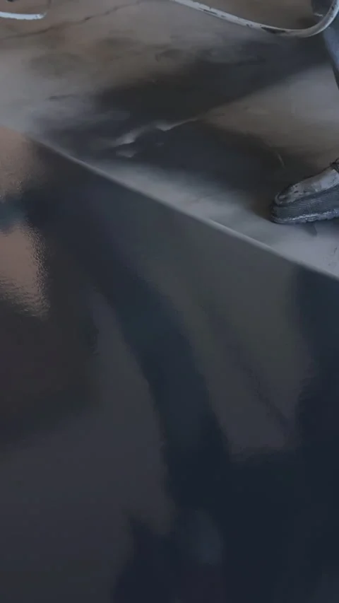 Worker spray paints large tabletop in renovated indoor space during painting day Stock Footage 342824972