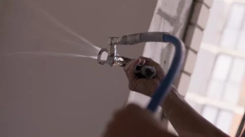 Worker spraying plaster onto interior wall using mechanical spray gun 動画素材 347745923