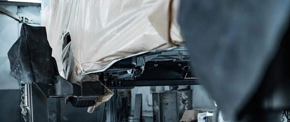 Worker Spraying Protective Undercoating Beneath a Car in Auto Workshop Stock Photos