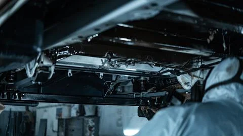 Worker Spraying Protective Undercoating Beneath a Car in Auto Workshop Stock Photos