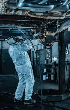 Worker Spraying Protective Undercoating Beneath a Car in Auto Workshop Stock Photos