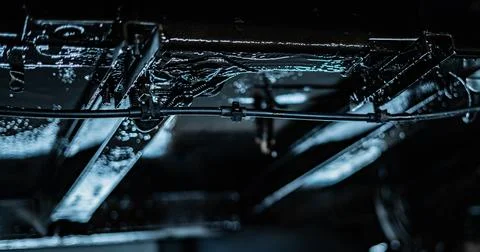 Worker Spraying Protective Undercoating Beneath a Car in Auto Workshop Stock Photos