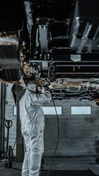 Worker Spraying Protective Undercoating Beneath a Car in Auto Workshop Stock Photos