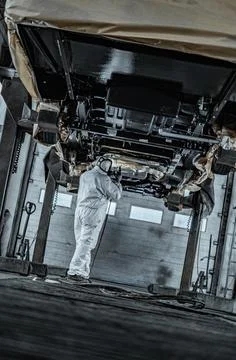 Worker Spraying Protective Undercoating Beneath a Car in Auto Workshop Stock Photos
