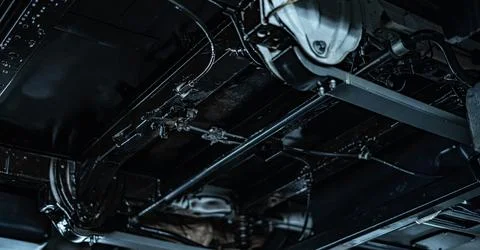Worker Spraying Protective Undercoating Beneath a Car in Auto Workshop Stock Photos