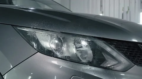 Worker sprays cleaning compound on car headlight and wipes with microfiber Stock Footage 141401579