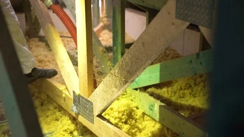 Worker sprays insulation into attic floor cavity between structural trusses Vidéo 312325228