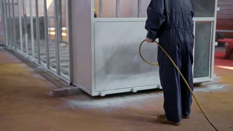 Worker sprays metal structure in industrial workshop during daytime production Stock Footage 310333418