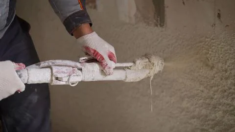 A worker sprays putty on a wall. The process of applying plaster to walls i.. Stock Photos