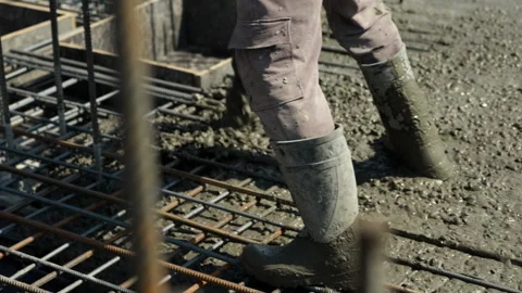 Worker spreading fresh concrete over steel reinforcement grid Stock Footage 344606301