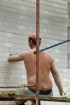 Worker spreading mortar over styrofoam insulation and mesh with trowel Stock Photos