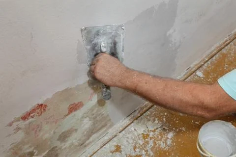 Worker spreading plaster to damaged wall Stock-Fotos