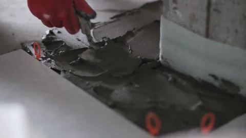 Worker spreading tile adhesive around concrete column Stock Footage 320786044