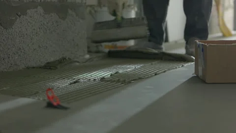 Worker spreading tile adhesive on floor during interior construction 스톡 동영상 344471342