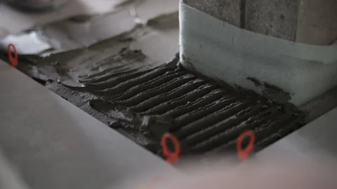 Worker spreading tile adhesive with notched trowel on floor Stock Footage 314236376
